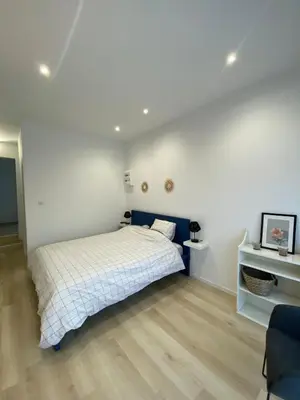 a white bedroom with a bed and a wooden floor at Studio en Provence avec piscine in La Barben