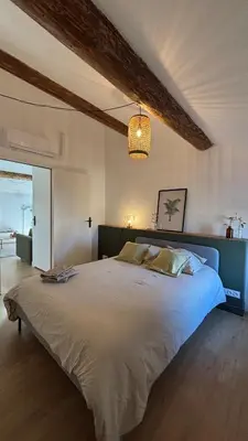 a bedroom with a large bed and a chandelier at Le Granier location in Robion en Luberon