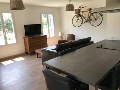 a living room with a table and a bike on the wall at Petite maison au calme avec piscine privative in Saint-Rémy-de-Provence