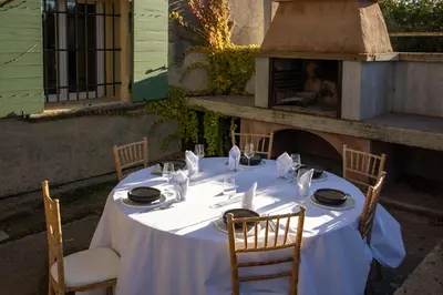 a table with a white table cloth and chairs and a fireplace at Domaine de la Myrtille in Pertuis