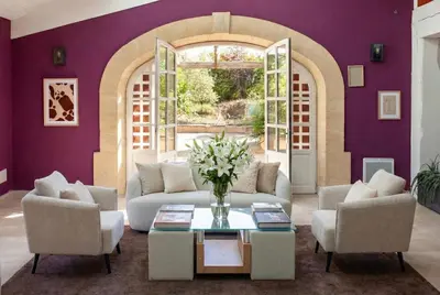a living room with purple walls and a vase of flowers at Domaine de la Myrtille in Pertuis