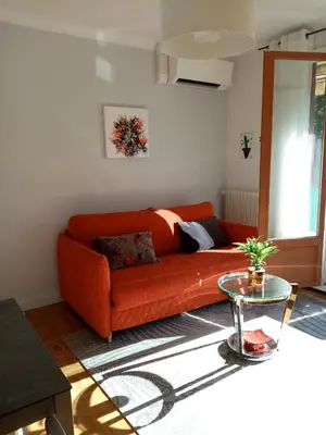 an orange couch in a living room with a table at Aix centre charmant T2 climatisé parc jourdan in Aix-en-Provence