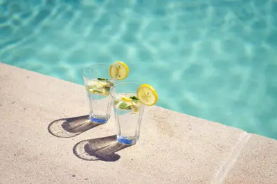 two glasses of lemonade sitting next to a swimming pool at Bastide Saint Maurin in Ansouis