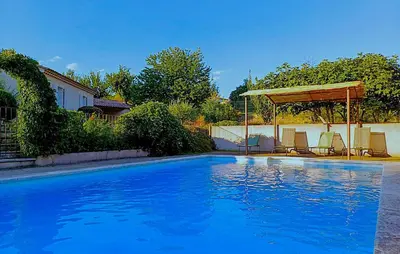 a blue swimming pool with a gazebo and chairs at Sarriette & Romarin in Apt