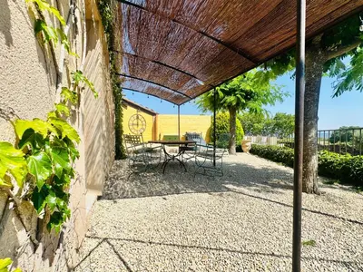 a patio with a table and chairs under a wooden roof at La Réserve Provence in Vaugines