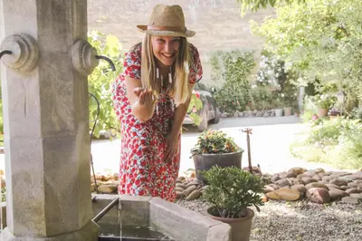 a woman in a hat standing next to a fountain at CHAMBRES D'HÔTES L'Oréliane en Provence Adults Only in Châteauneuf-de-Gadagne