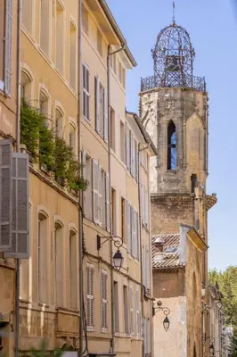 an old building with a clock tower in a street at Charme et Modernité au coeur d'Aix & Cours Mirabeau in Aix-en-Provence