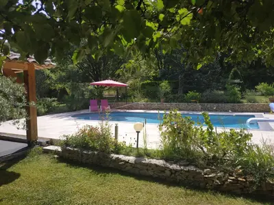 a swimming pool with an umbrella and some plants at AU BONHEUR et LIBERTÉ in Meyrargues