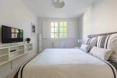 a white bedroom with a large bed and a television at Le Jardinet de la Cathédrale in Aix-en-Provence