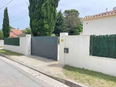 a gate in a white fence next to a house at Duplex indépendant avec clim et parking St Donat in Aix-en-Provence