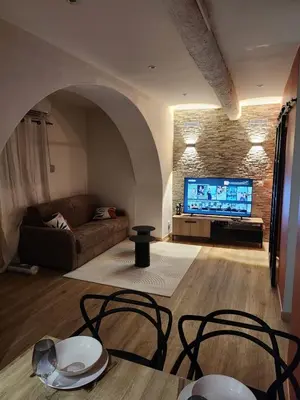 a living room with a couch and a tv at Escapade sur la Sorgue in LʼIsle-sur-la-Sorgue