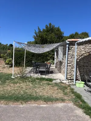 a patio with a table and chairs and a stone wall at Le pavé in Gordes
