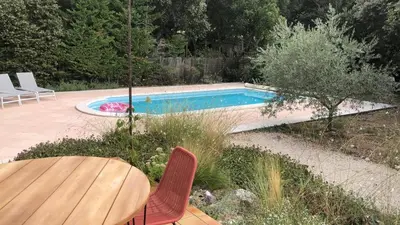 a swimming pool with a table and chairs next to it at La maison du bon remède in Mazan
