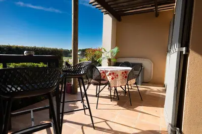 a patio with a table and chairs on a balcony at Appartement au coeur du Golf de Saumane in Saumane-de-Vaucluse