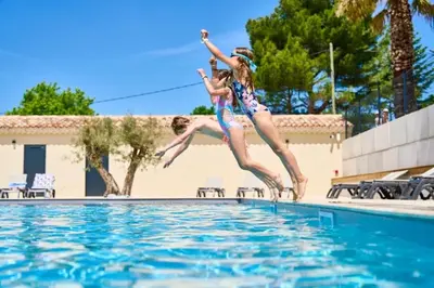 two girls jumping into a swimming pool at Camping 3 étoiles - Piscine - efaeh0 in Malemort-du-Comtat