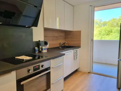 a kitchen with white cabinets and a sink and a window at Bright T2 - parking - AC in Aix-en-Provence