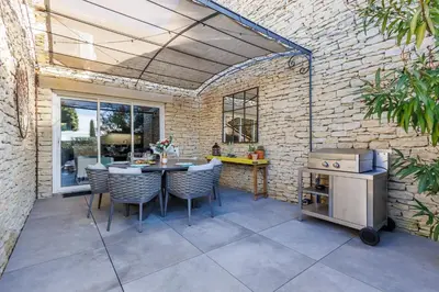 a patio with a table and chairs and a stove at Basti Lou - Proche du village de Gordes in Gordes