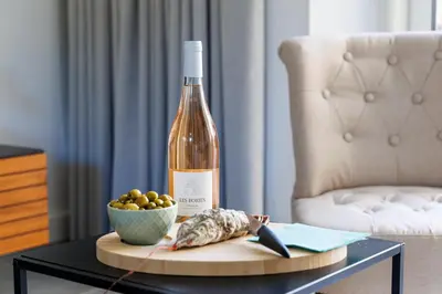 a bottle of wine and a bowl of fruit on a table at Basti Lou - Proche du village de Gordes in Gordes