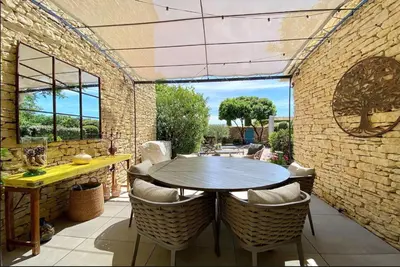 an outdoor patio with a wooden table and chairs at Basti Lou - Proche du village de Gordes in Gordes