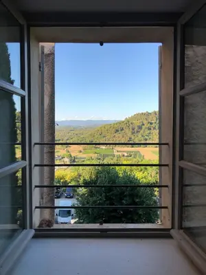 an open window with a view of a field at Le charme au centre du village in Ménerbes
