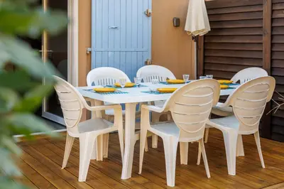a white dining room table and chairs on a deck at Bastidon Provençal - Avec piscine partagée in Aubignan