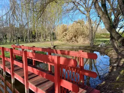 a red bench in a park next to a pond at Maison au bord de l'eau in Le Thor