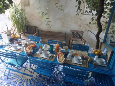 a table with blue chairs and food on it at Gite Fa Mille maison bleu in Robion en Luberon