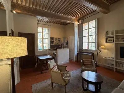 a living room with chairs and a table and a kitchen at Bel appartement aixois dans le centre historique in Aix-en-Provence
