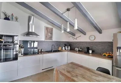 a kitchen with white cabinets and a wooden table at Maison méditerranéenne 130m piscine Vaucluse in Carpentras