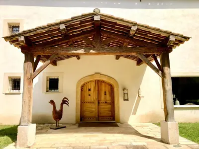 a house with a wooden door and a chicken statue in front at Villa Provençale - Rognes campagne d'Aix en Provence in Rognes
