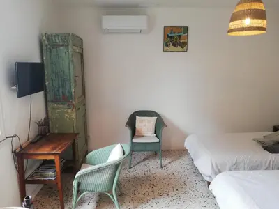 a room with two beds and a chair and a desk at Gîte de la treille in LʼIsle-sur-la-Sorgue