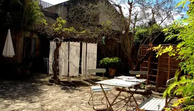 a table and chairs in a yard with a fence at Ancienne Maison des Gardes in Lourmarin