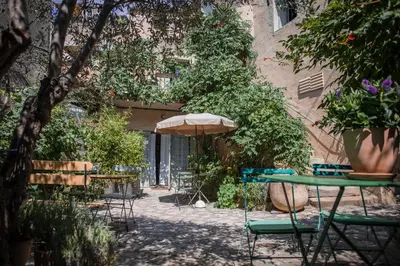a patio with tables and chairs and an umbrella at Ancienne Maison des Gardes in Lourmarin