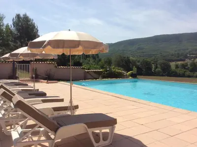 a swimming pool with lounge chairs and an umbrella at Domaine de la Bastidonne in Céreste
