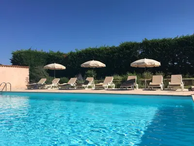 a group of chairs and umbrellas next to a swimming pool at Domaine de la Bastidonne in Céreste