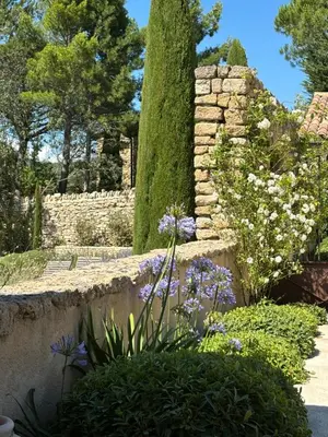 a garden with purple flowers and a stone wall at Le jardin suspendu in Gordes