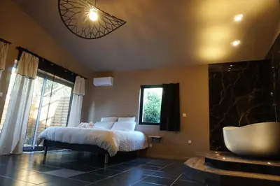 a bedroom with a bed and a tub and a window at Chambre de charme indépendante Alba avec baignoire îlot - Domaine Astra, Grans in Grans