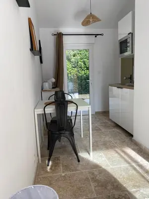 a room with a table with a clock and a window at Le studio de Marie in Noves