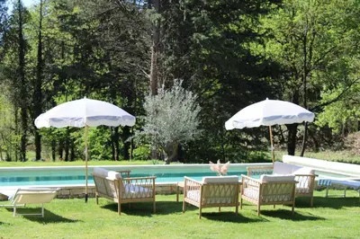 a group of chairs and umbrellas next to a pool at Quiet Provencal bastide with pool close Lourmarin in Lauris