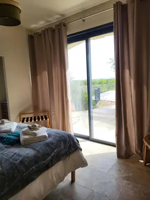 a bedroom with a bed and a sliding glass door at La Bastide des Amis in Caromb