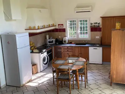 a kitchen with a table and a white refrigerator at Maison d'hôte en Provence avec petit déjeuner in Mollégès