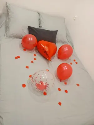 a bed with red balloons and confetti on it at studio in Morières-lès-Avignon