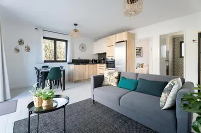 a living room with a couch and a table and a kitchen at La maison d'Alice - Calme - Climatisation - Parking privatif in Velaux