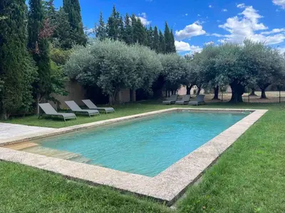 a swimming pool in a yard with chairs and trees at Le mas provençal d'Aurélie in Carpentras