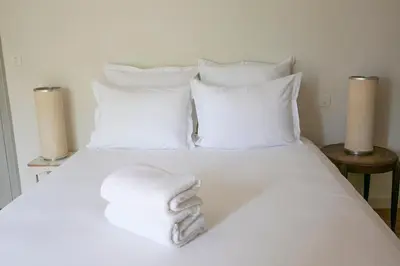 a white towel laying on a white bed with pillows at Le mas provençal d'Aurélie in Carpentras