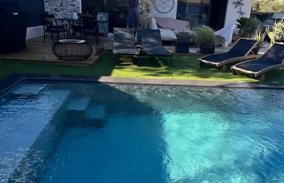 a swimming pool with chairs and a table in a yard at Chambres d'hôte in Châteauneuf-de-Gadagne