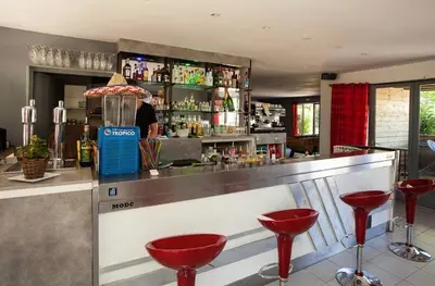 a bar with red stools and a man behind the counter at Mobilhome 6 personnes in Cheval-Blanc