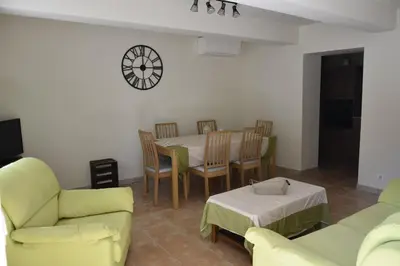 a living room with a table and chairs and a clock at Gite chez les Truph in Entraigues-sur-la-Sorgue