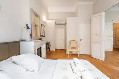 a white bedroom with a bed and a fireplace at Bel appartement près du Cours Mirabeau in Aix-en-Provence