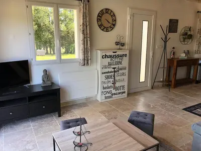 a living room with a table and a clock on the wall at Maison de charme in Monteux